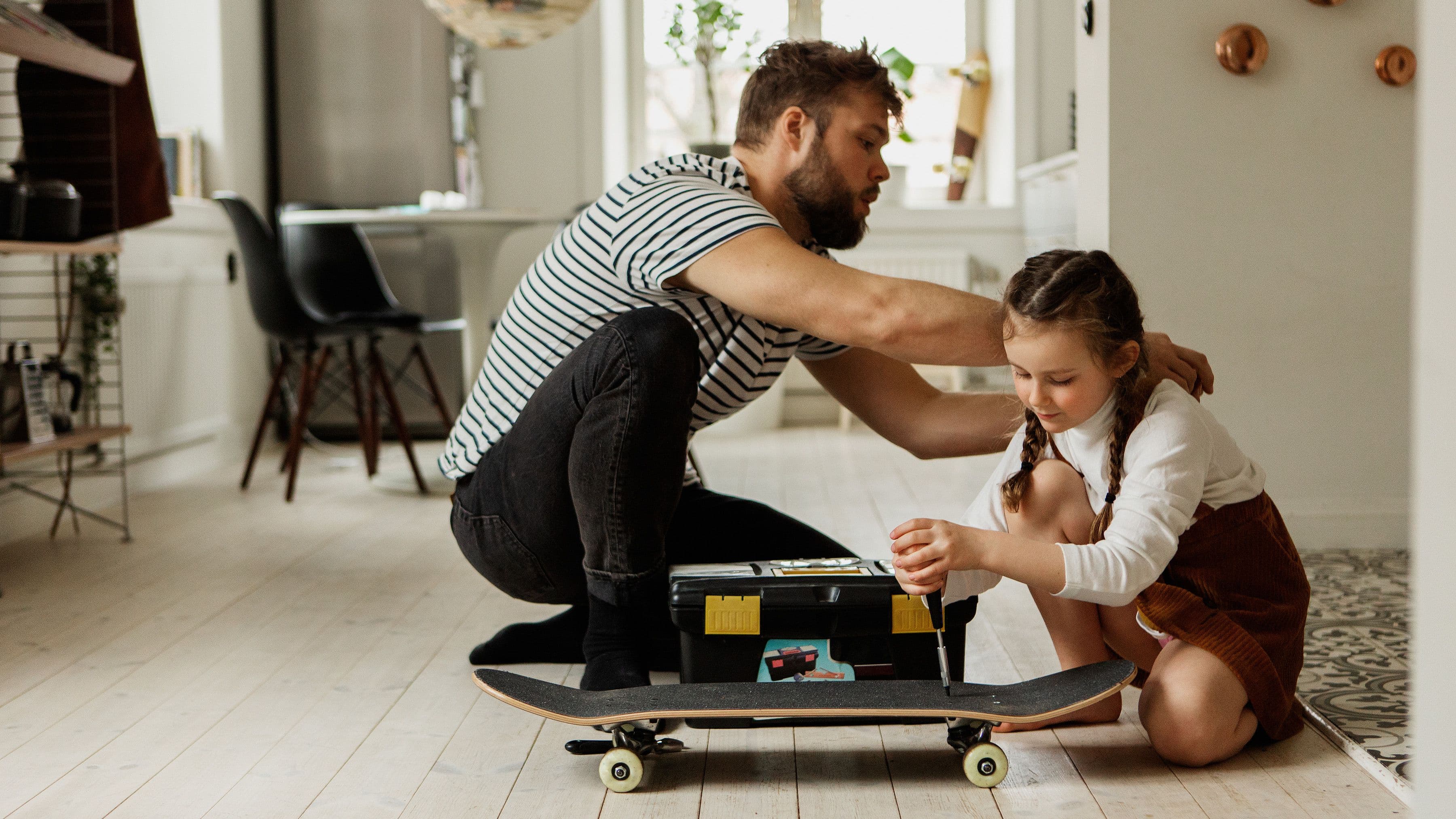 pappa och dotter meckar med skateboard